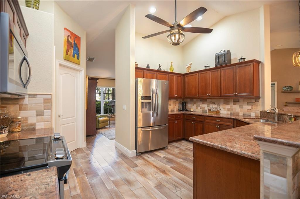 1207 Imperial Drive Naples, FL 34110 - Photo 5 of 15 a kitchen with granite countertop a refrigerator a sink dishwasher stove and oven with wooden floor