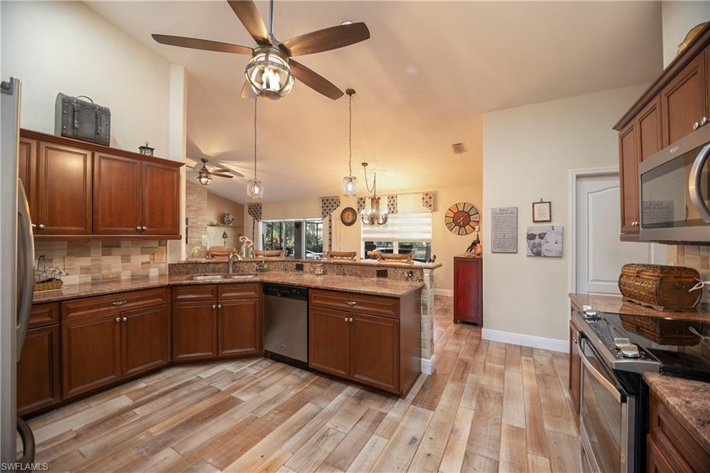 1207 Imperial Drive Naples, FL 34110 - Photo 6 of 15 a kitchen with stainless steel appliances granite countertop a sink a stove and refrigerator