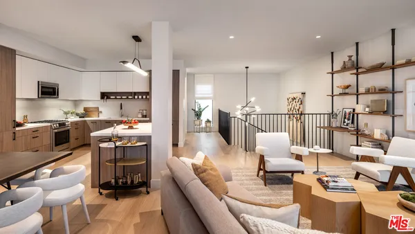 a living room with furniture kitchen view and a wooden floor