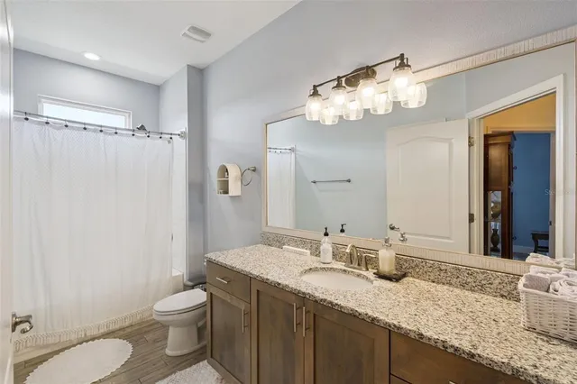 a bathroom with a granite countertop sink toilet and shower