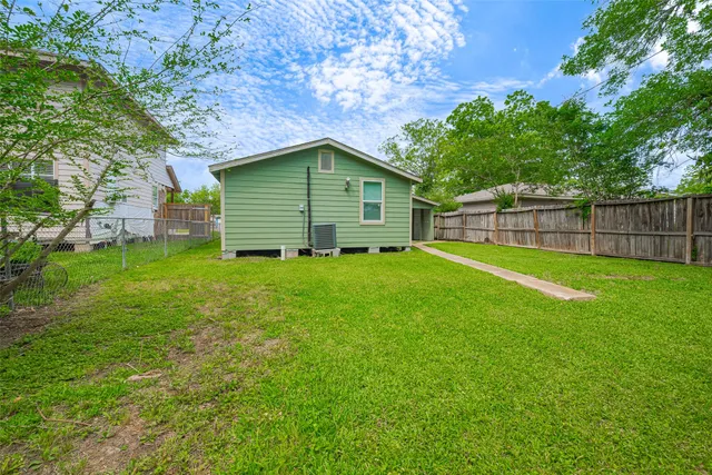 a backyard of a house with large trees and wooden fence
