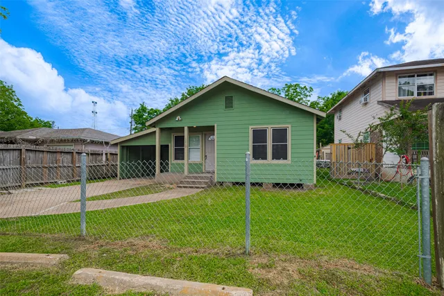 a view of a yard in front of a house with plants and large tree