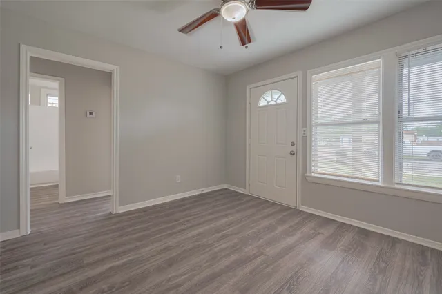 an empty room with wooden floor cabinet and windows