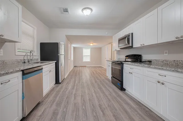 a kitchen with granite countertop a stove top oven a sink dishwasher and a refrigerator with wooden floor