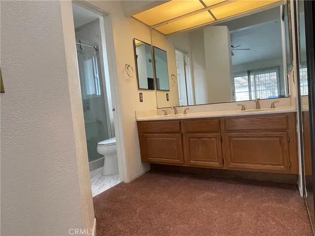 a spacious bathroom with a double vanity sink a toilet and a mirror