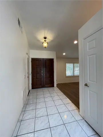 a view of an empty room with window and chandelier fan