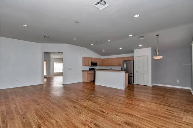 a view of kitchen with kitchen island wooden floor center island and stainless steel appliances