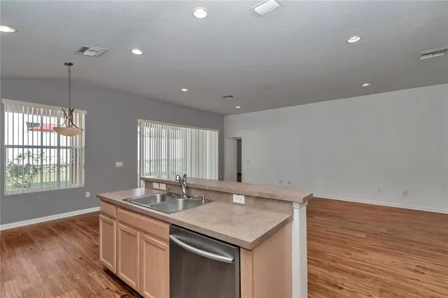 a kitchen with granite countertop a sink and dishwasher with wooden floor