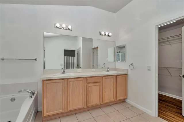 a bathroom with a double vanity sink mirror and bathtub