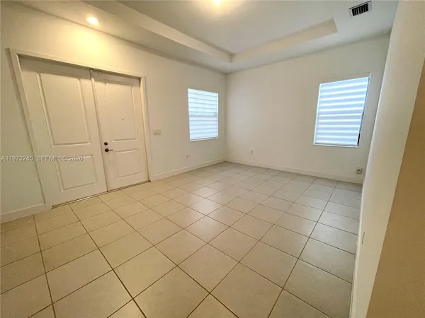 a view of an empty room with kitchen view and window