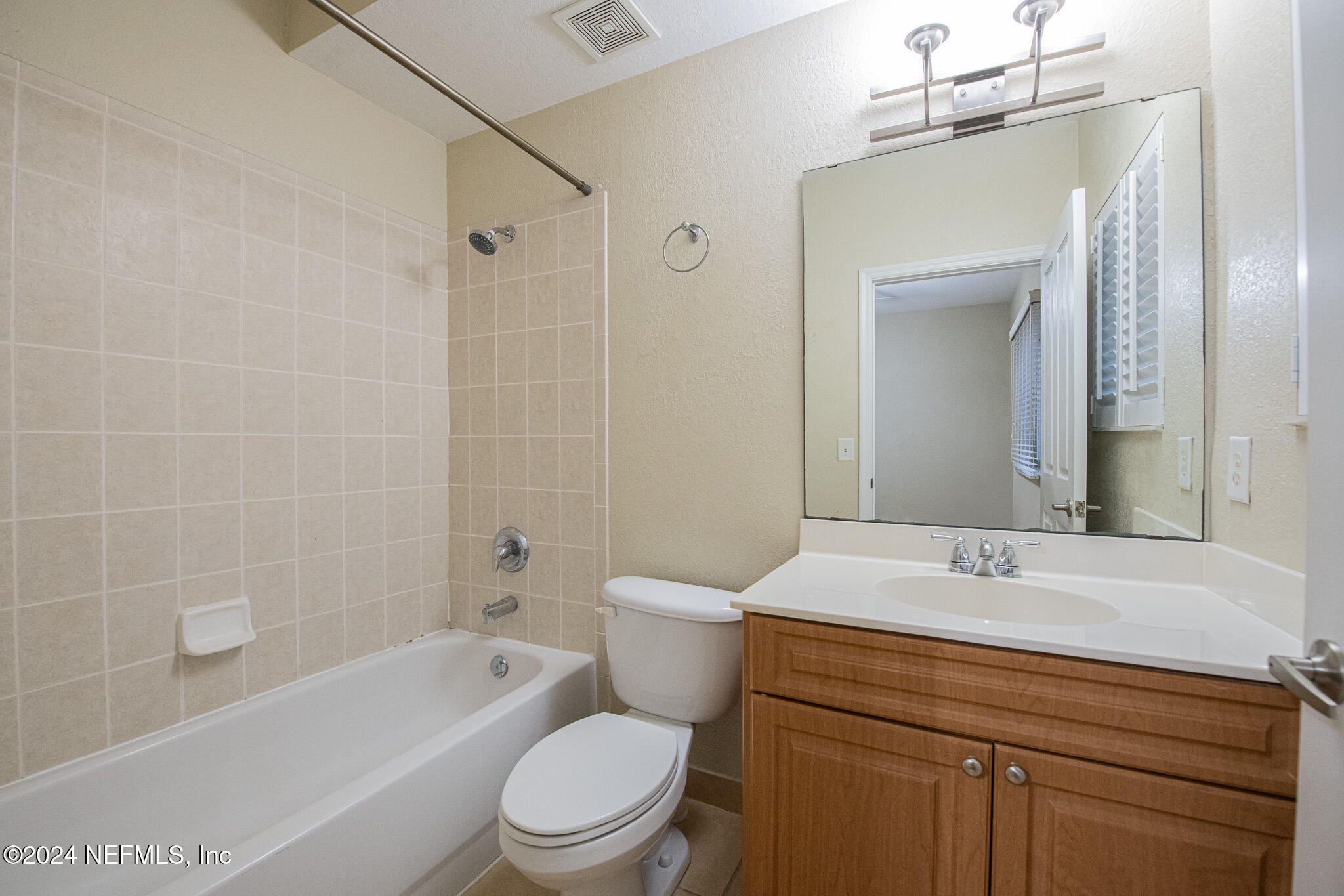 9745 Touchton Road, Unit 1922 Jacksonville, FL 32246 - Photo 16 of 26 a bathroom with a sink a toilet a mirror a bathtub and shower
