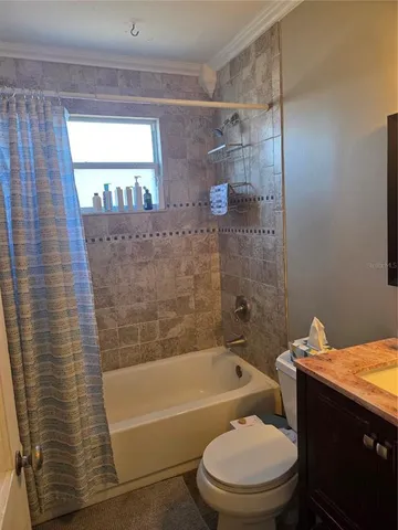 a bathroom with a granite countertop bathtub shower sink vanity and toilet