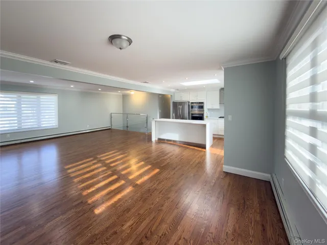 a living room with stainless steel appliances kitchen island granite countertop wooden floors a stove and a sink