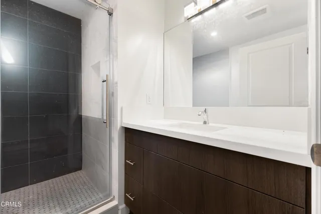 a bathroom with a sink shower and a mirror