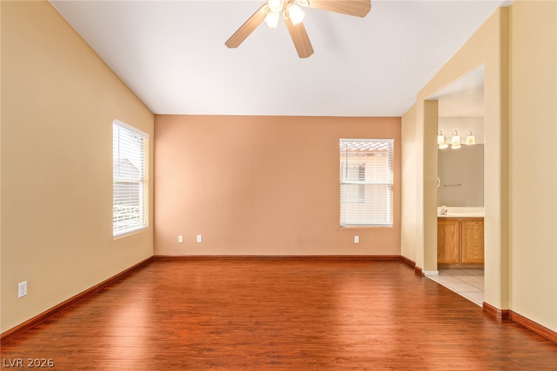 1477 Rancho Ridge Drive Henderson, NV 89012 - Photo 18 of 46 Well-lit primary bedroom featuring polished hardwood floors and direct access to a private bathroom.