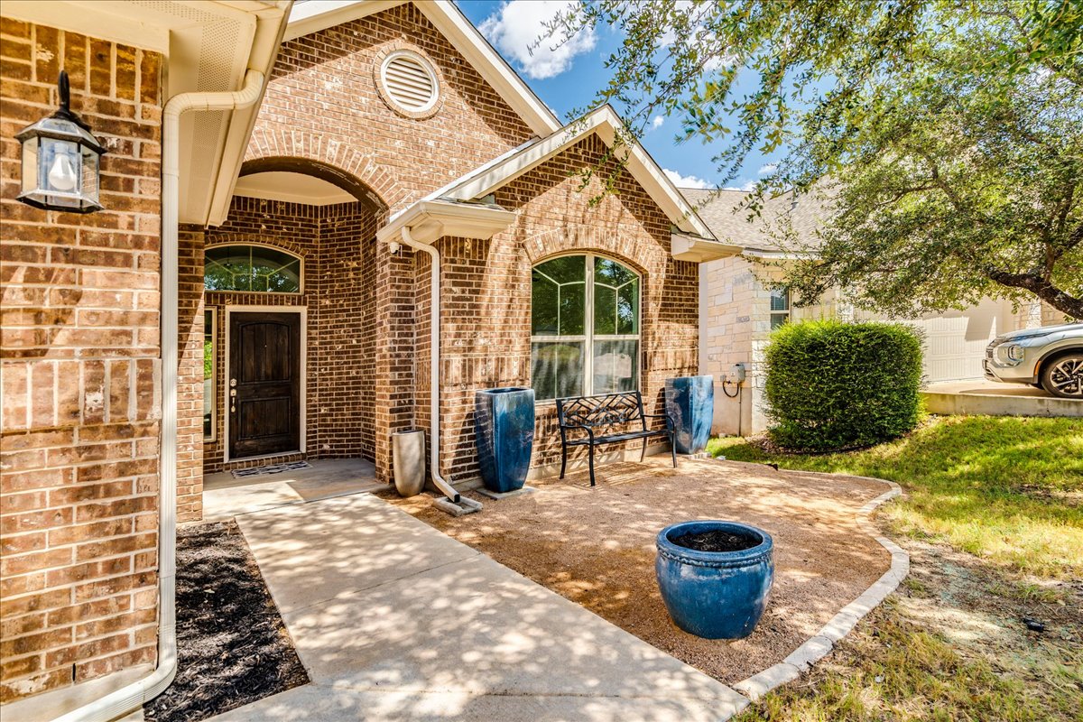 5009 Inks Clearing Lane Austin, TX 78738 - Photo 5 of 34 A classic brick exterior surrounds a welcoming recessed entry and structured concrete pathway.