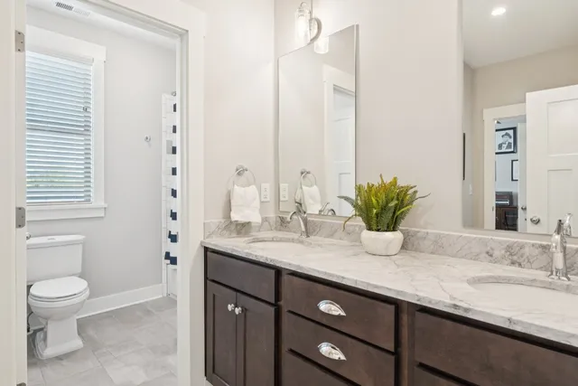 a bathroom with a granite countertop sink a toilet and mirror