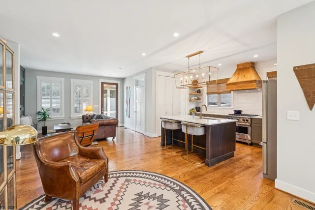 a living room with stainless steel appliances kitchen island granite countertop a couch and wooden cabinets