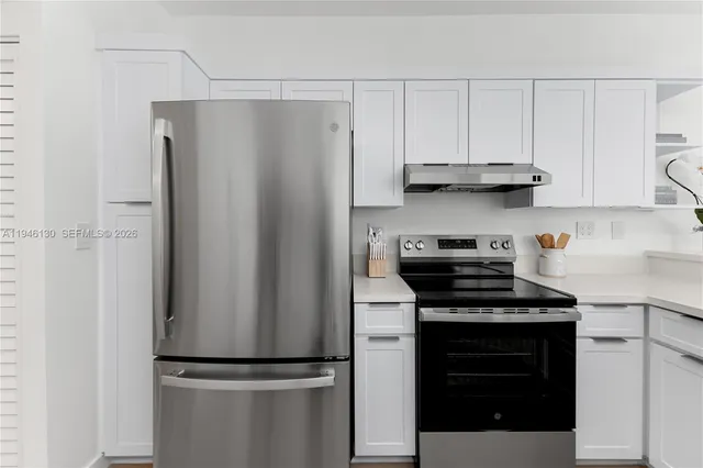 a kitchen with stainless steel appliances granite countertop a refrigerator and a stove top oven