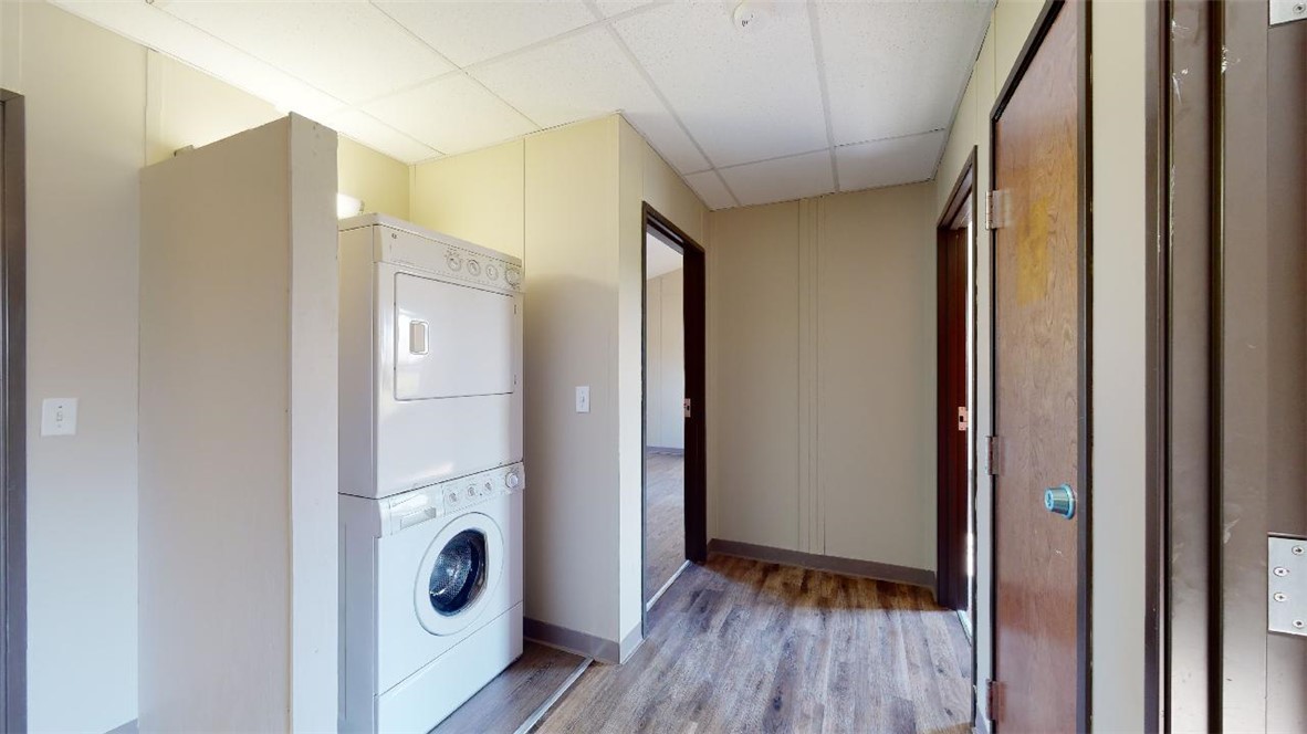 5585 Straub Road, Unit 110 College Station, TX 77845 - Photo 7 of 14 Laundry room featuring a paneled ceiling, stacked washer / dryer, and light wood-style flooring