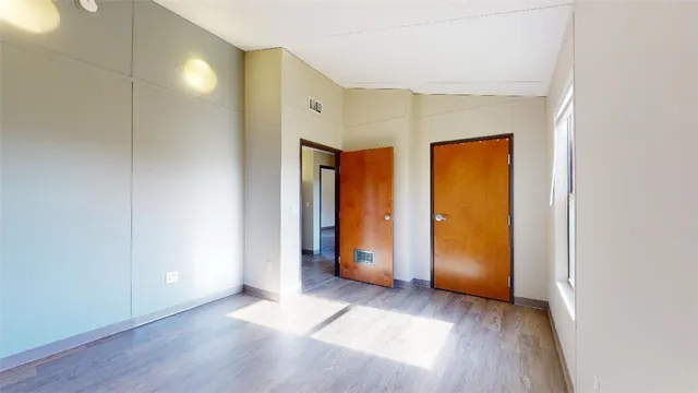 a view of an empty room with closet and wooden floor