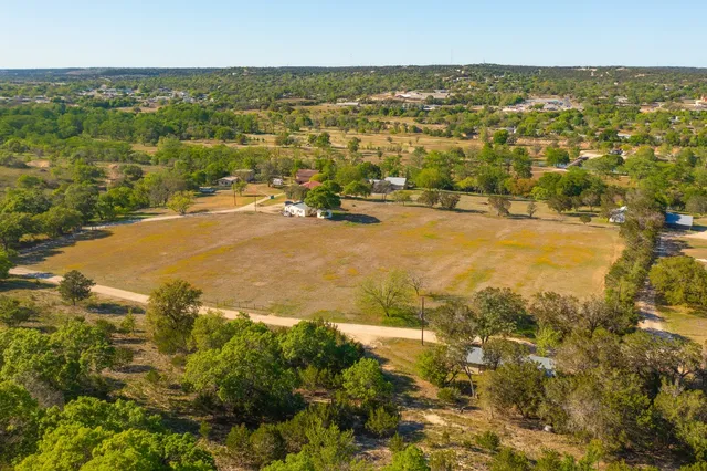 an aerial view of residential houses with outdoor space and trees