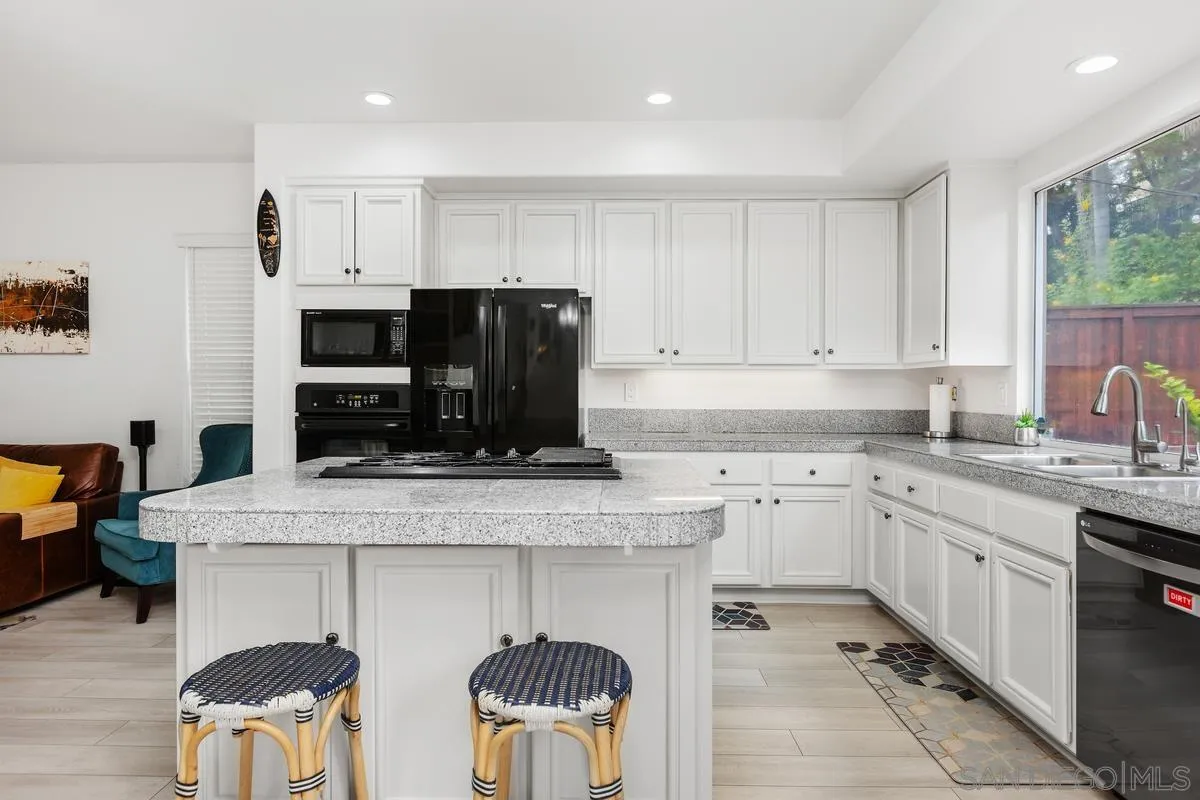 13847 Carmel Ridge Road San Diego, CA 92128 - Photo 9 of 40 a kitchen with stainless steel appliances granite countertop a stove top oven a sink dishwasher and white cabinets with wooden floor