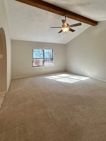 a view of an empty room with a ceiling fan and window