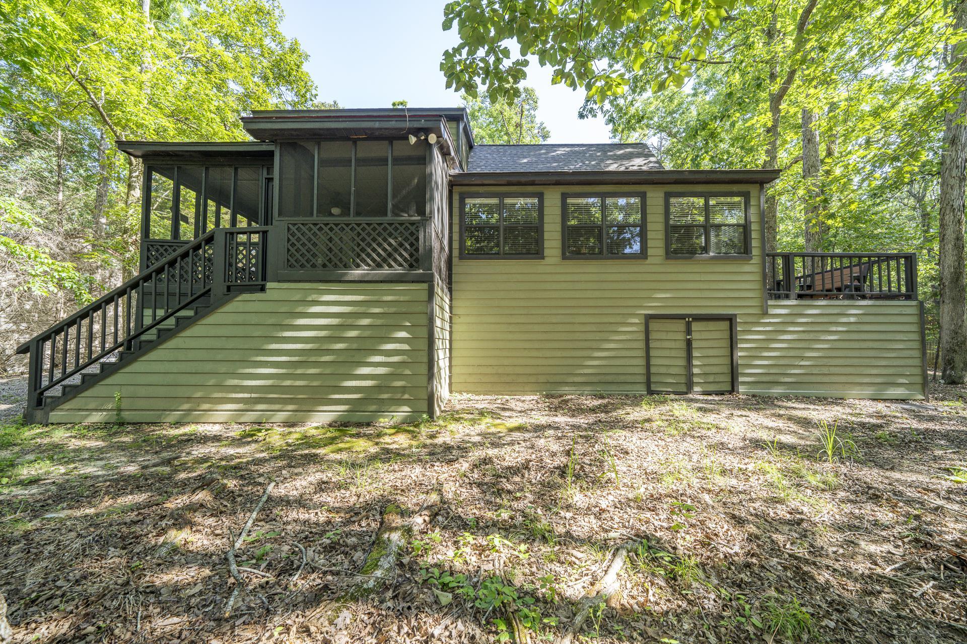 435 Murray Lane Counce, TN 38326 - Photo 33 of 34 Exterior featuring a screened porch with lattice railing, an exterior staircase with dark handrails, multiple windows, and an outdoor deck area