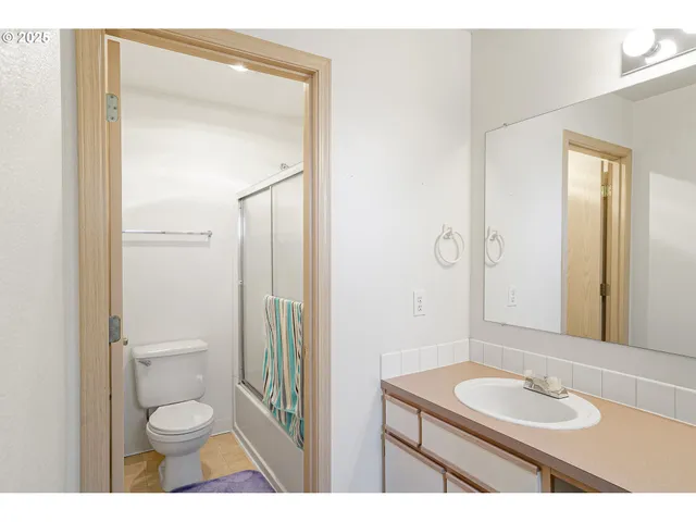 a bathroom with a granite countertop sink toilet a mirror and shower