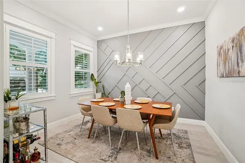 a view of a dining room with furniture a chandelier and large windows