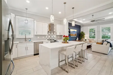 a kitchen with stainless steel appliances kitchen island granite countertop a refrigerator a sink dishwasher a dining table and chairs