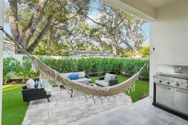 a view of a patio with table and chairs potted plants and large tree