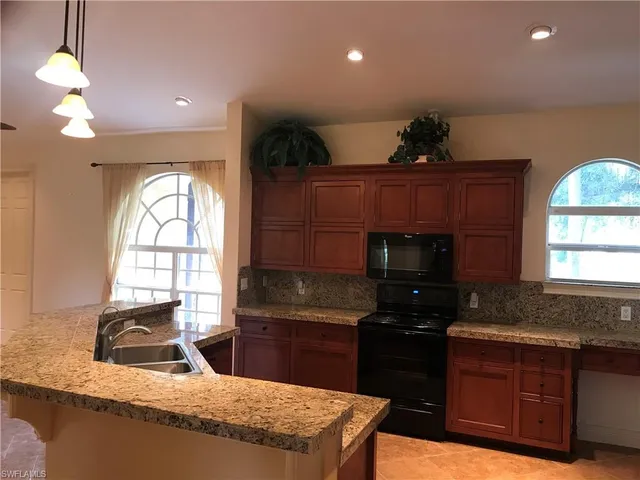 a kitchen with granite countertop a stove a sink and a microwave