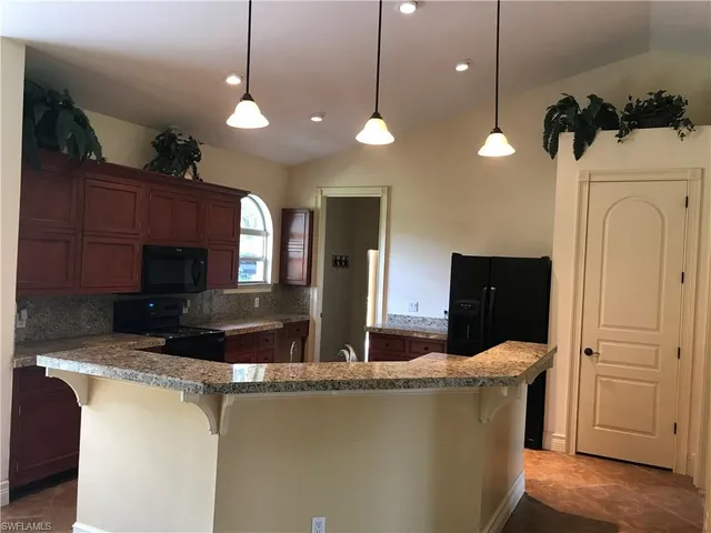 a view of a kitchen with kitchen island stainless steel appliances wooden floor and living room view