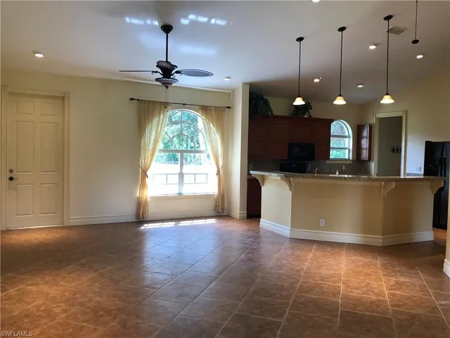 a view of a kitchen with a fireplace a ceiling fan and wooden floor