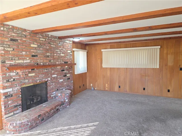 an empty room with wooden floor fireplace and windows