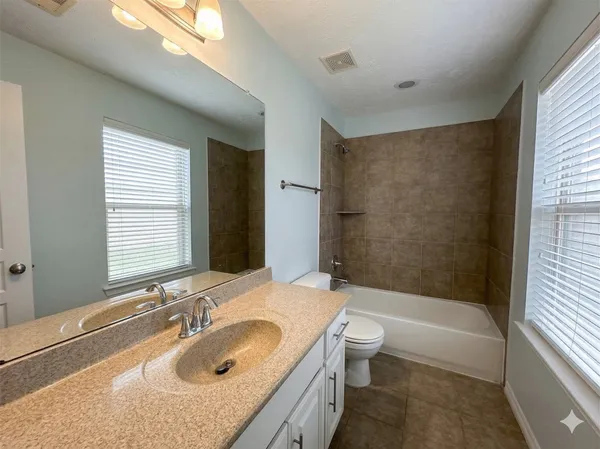 a bathroom with a granite countertop sink a toilet and shower