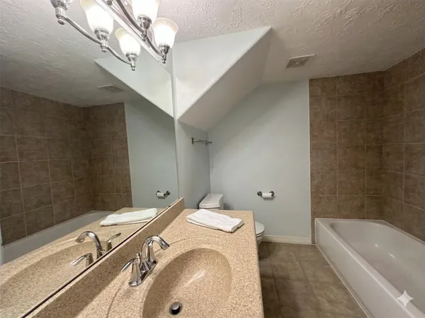 a bathroom with a granite countertop sink a toilet and bathtub