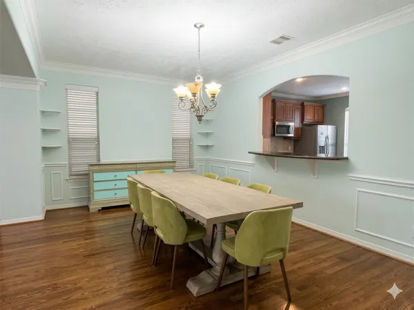 a dining room with wooden floor a chandelier a wooden table and chairs