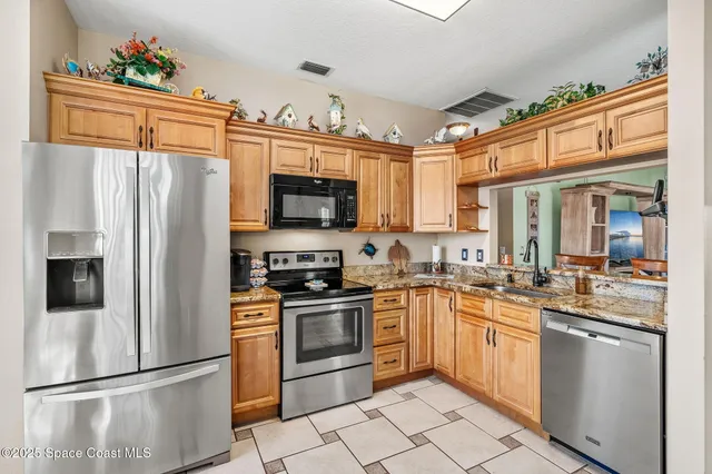 a kitchen with stainless steel appliances granite countertop a refrigerator sink stove microwave and cabinets