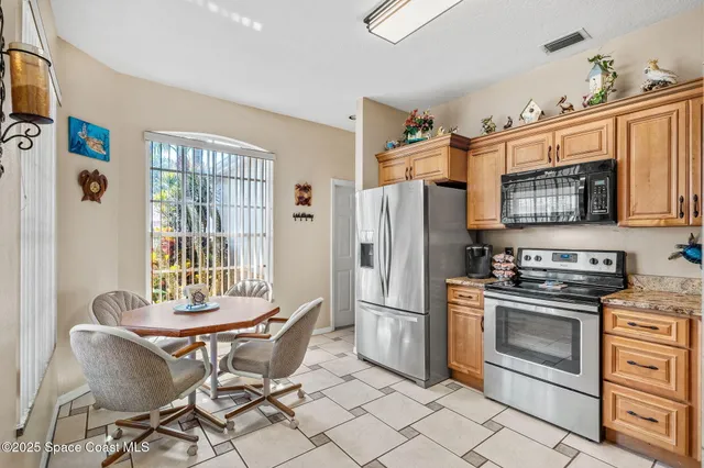 a kitchen with stainless steel appliances granite countertop a stove top oven a refrigerator and a dining table