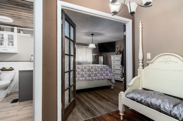 100 Third North Helper, UT 84526 - Photo 20 of 30 Rustic wood-finish flooring extends from the bedroom through a doorway into a bathroom featuring a toilet with white wainscoting