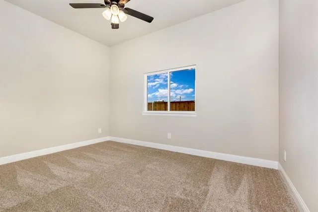 an empty room with a chandelier fan and windows