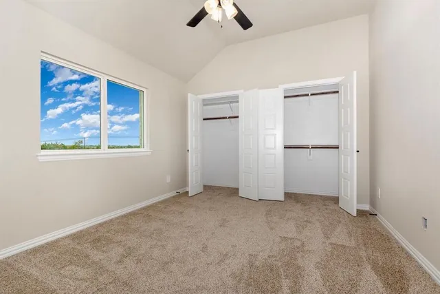 an empty room with chandelier fan and windows