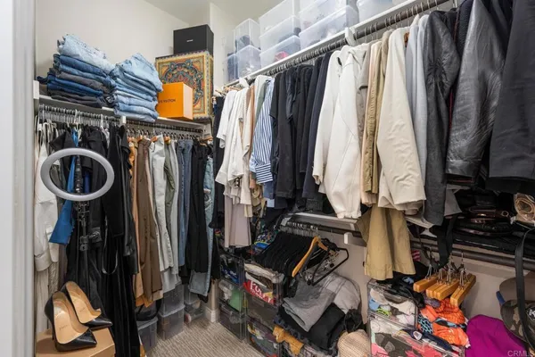 a view of walk in closet with clothes and shoes