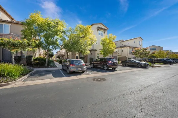 a view of road with card parked on side and retail shops