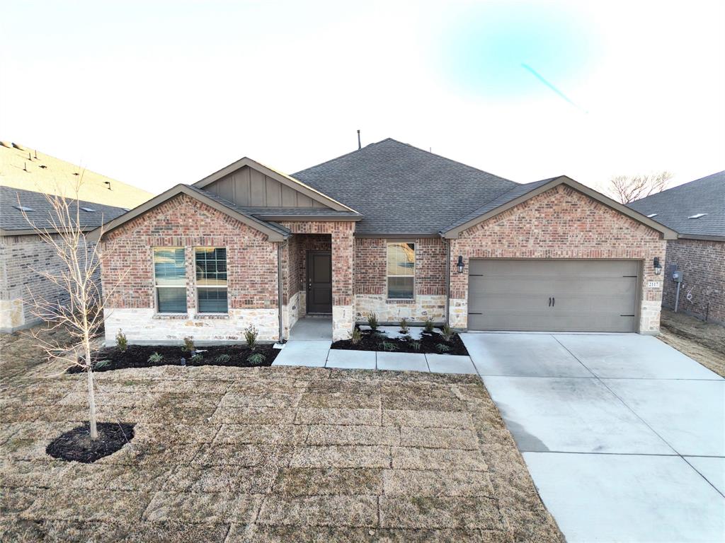View of front facade featuring driveway, board and batten siding, a garage, roof with shingles, and stone siding