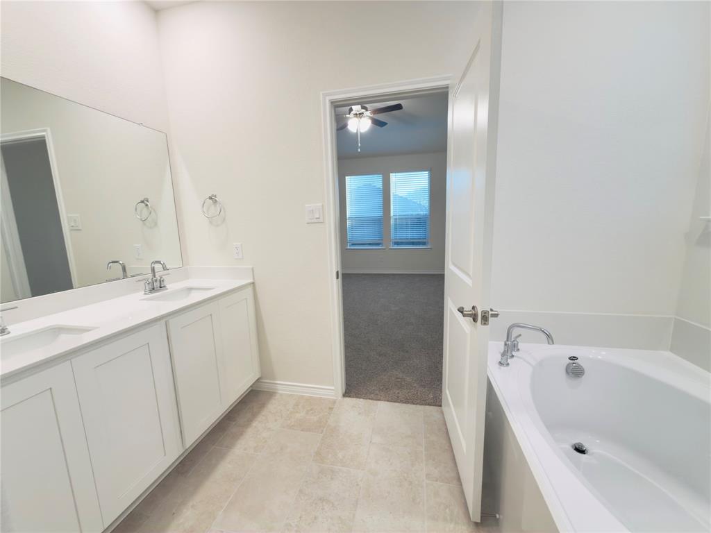 2117 Eugene Street Anna, TX 75409 - Photo 19 of 31 Bathroom with double vanity, a garden tub, light carpet, light tile patterned floors, and a ceiling fan