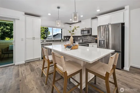 a kitchen with a dining table chairs refrigerator and microwave